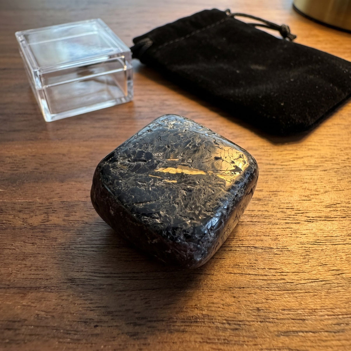 A polished nuummite on a desk beside a display case and a velvet bag