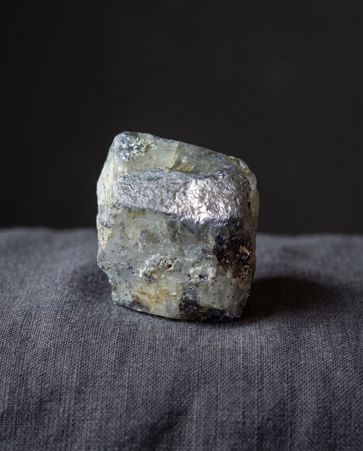 A phenacite crystal on dark linen